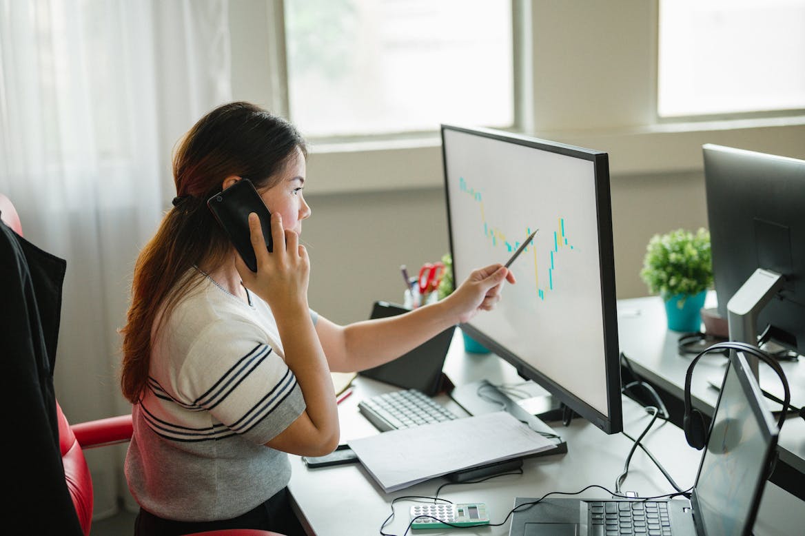 Girl on the phone pointing at a computer Girl on the phone pointing at a computer