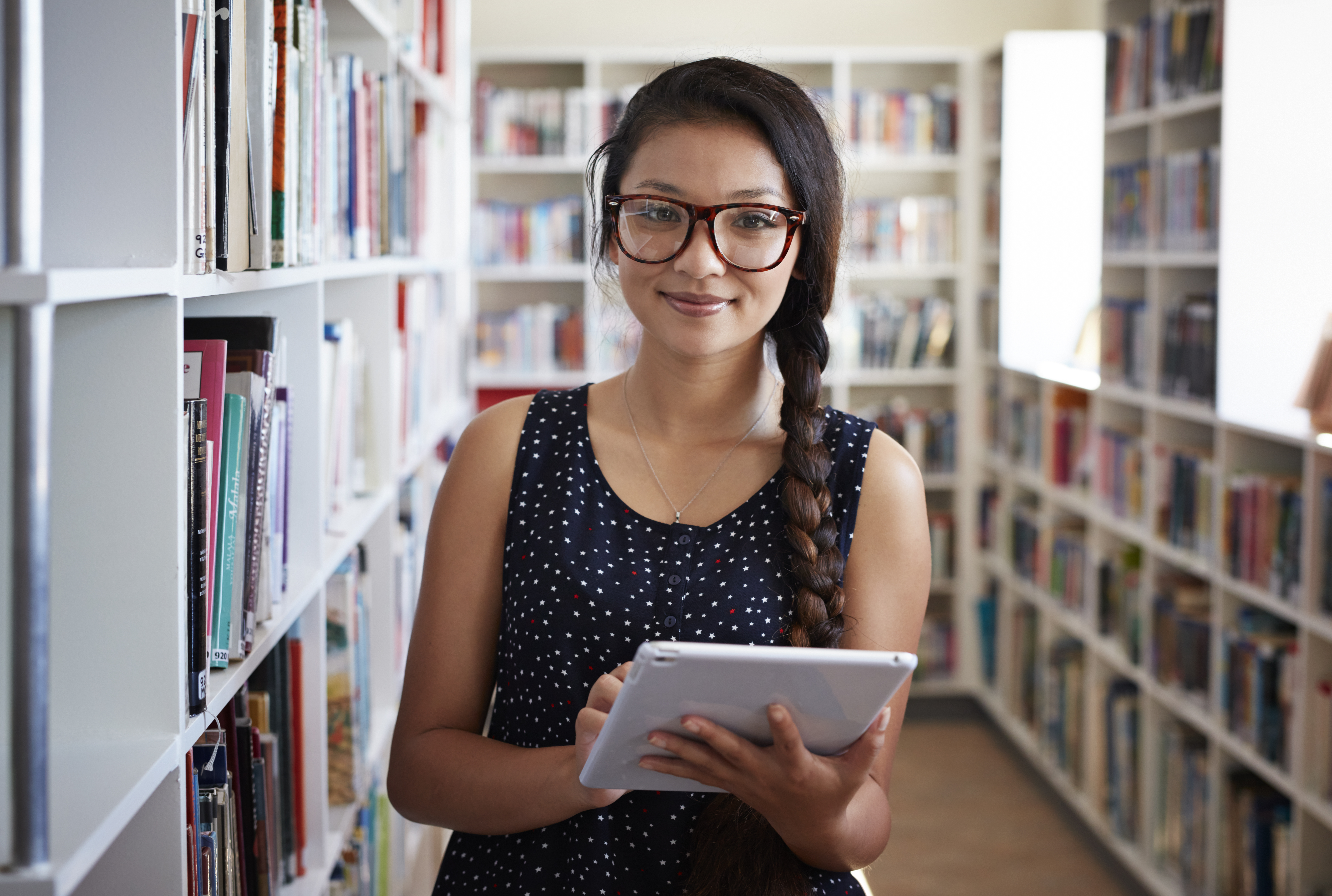 student holding a tablet at the library