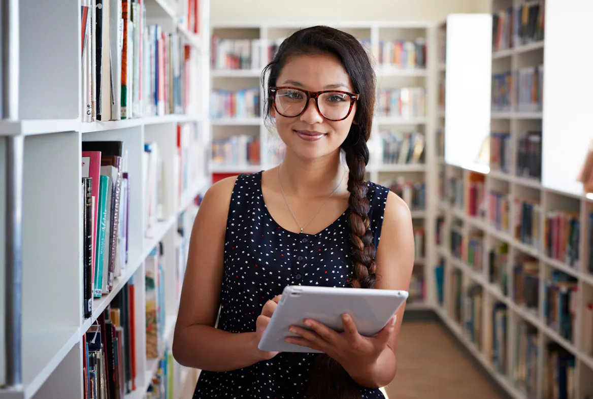 student holding a tablet at the library student holding a tablet at the library