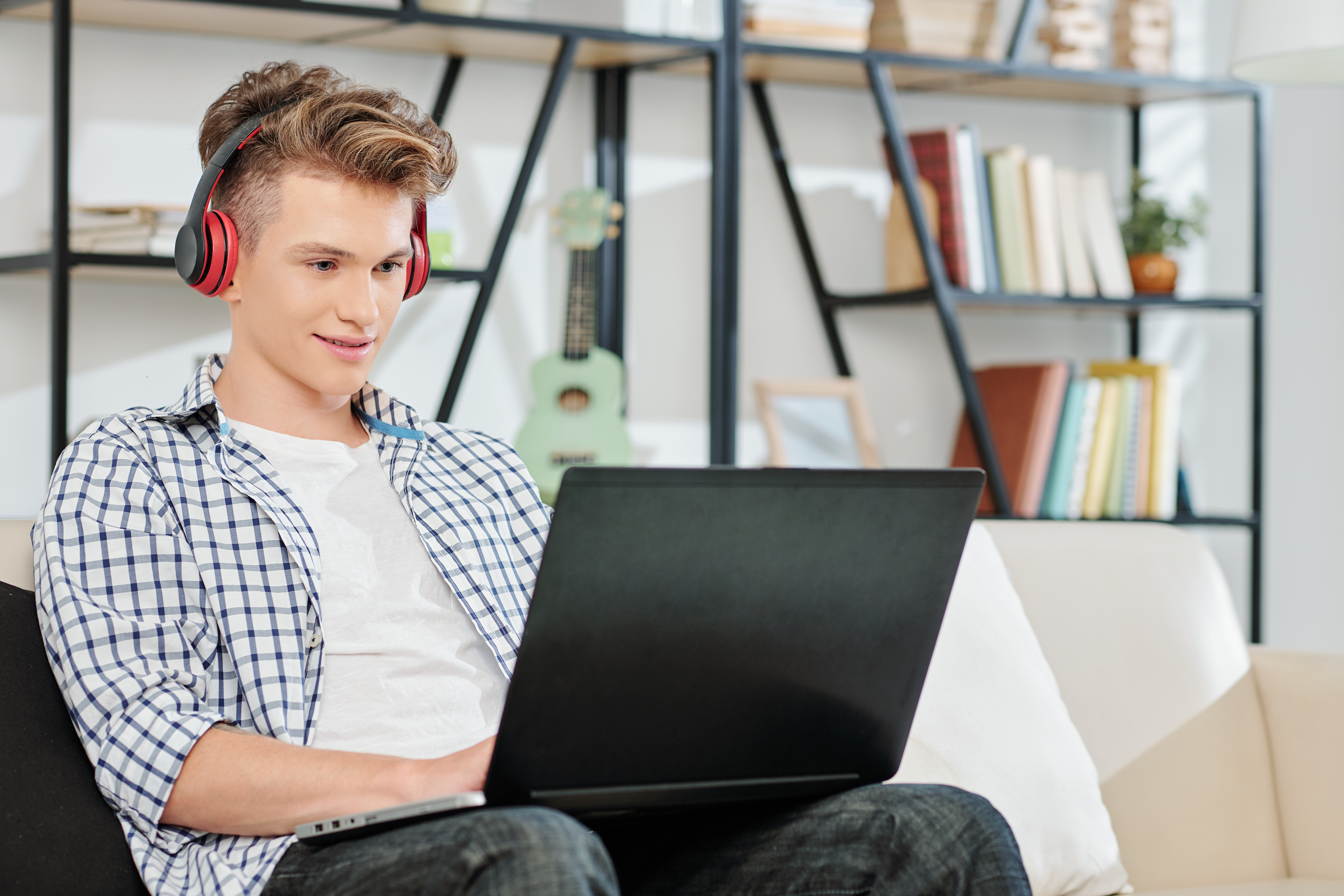 Student on laptop in living room with headphones