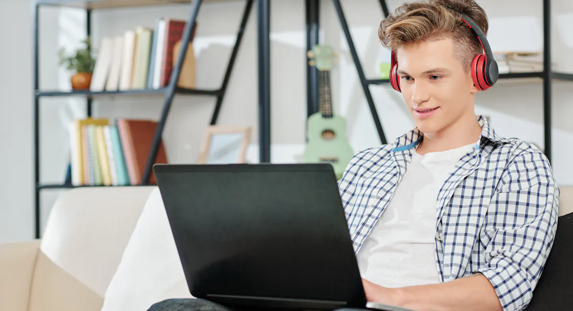 Student on laptop in living room with headphones Student on laptop in living room with headphones