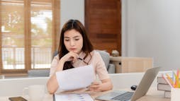Woman at desk reviewing sheets Woman at desk reviewing sheets