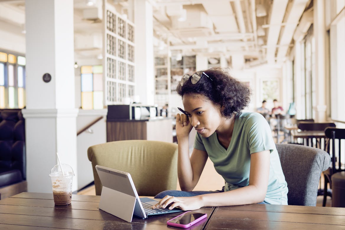 Person studying in a library with laptop Person studying in a library with laptop