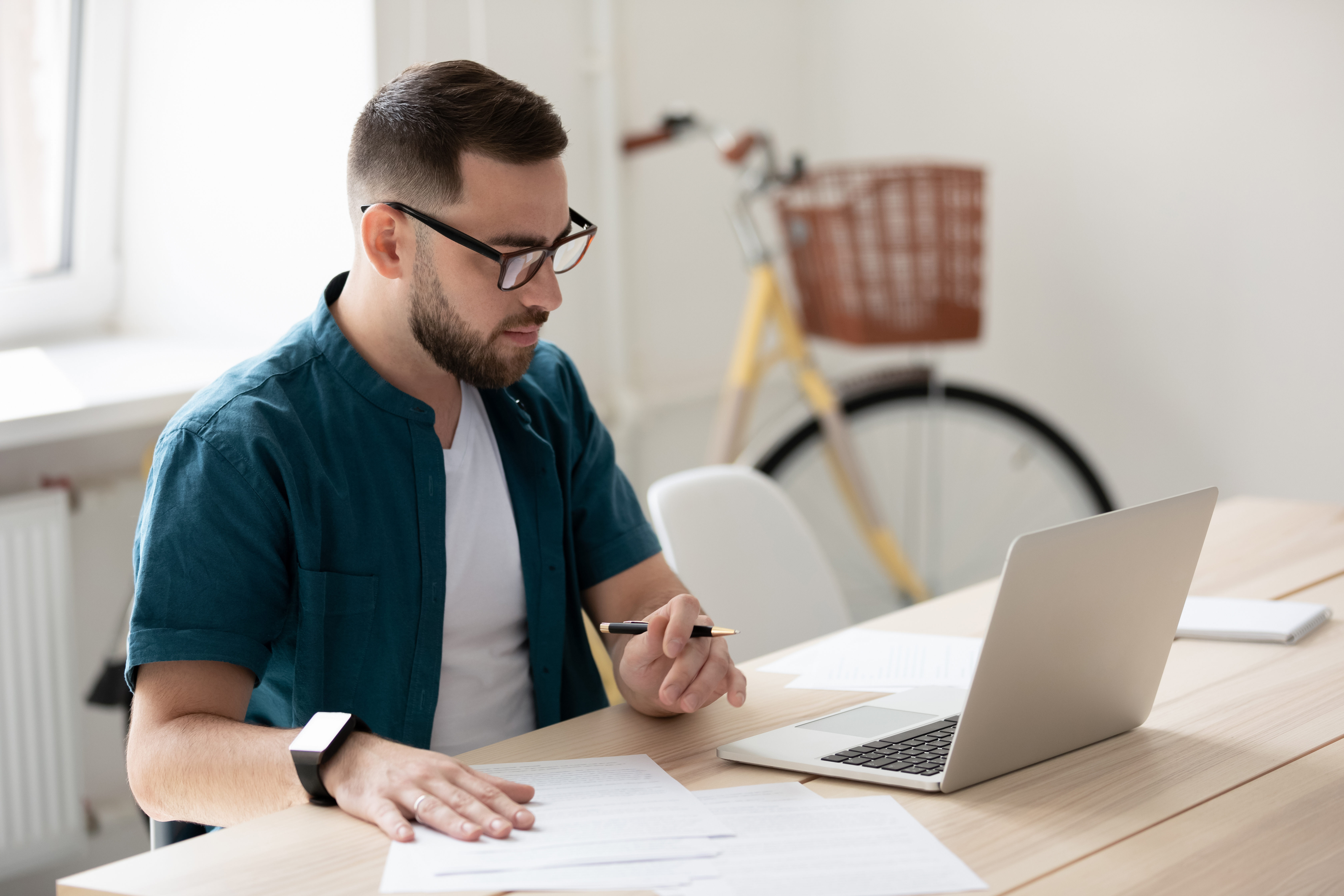 Man sitting in a loft office ona computer with worksheets