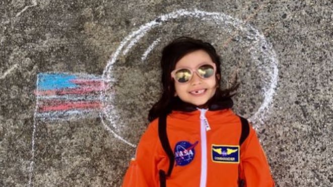 女孩打扮成宇航员，用粉笔画画