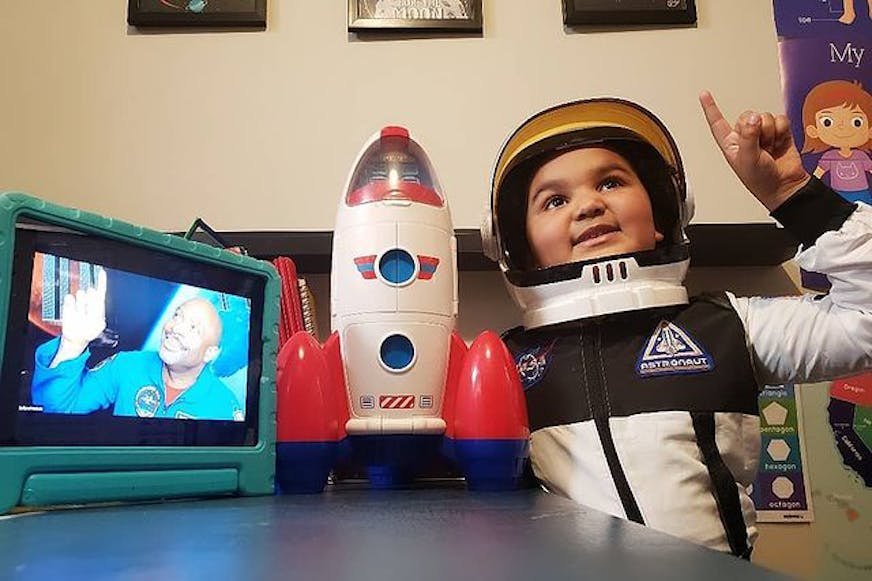 男孩打扮成宇航员，拿着火箭玩具和StarCourse
