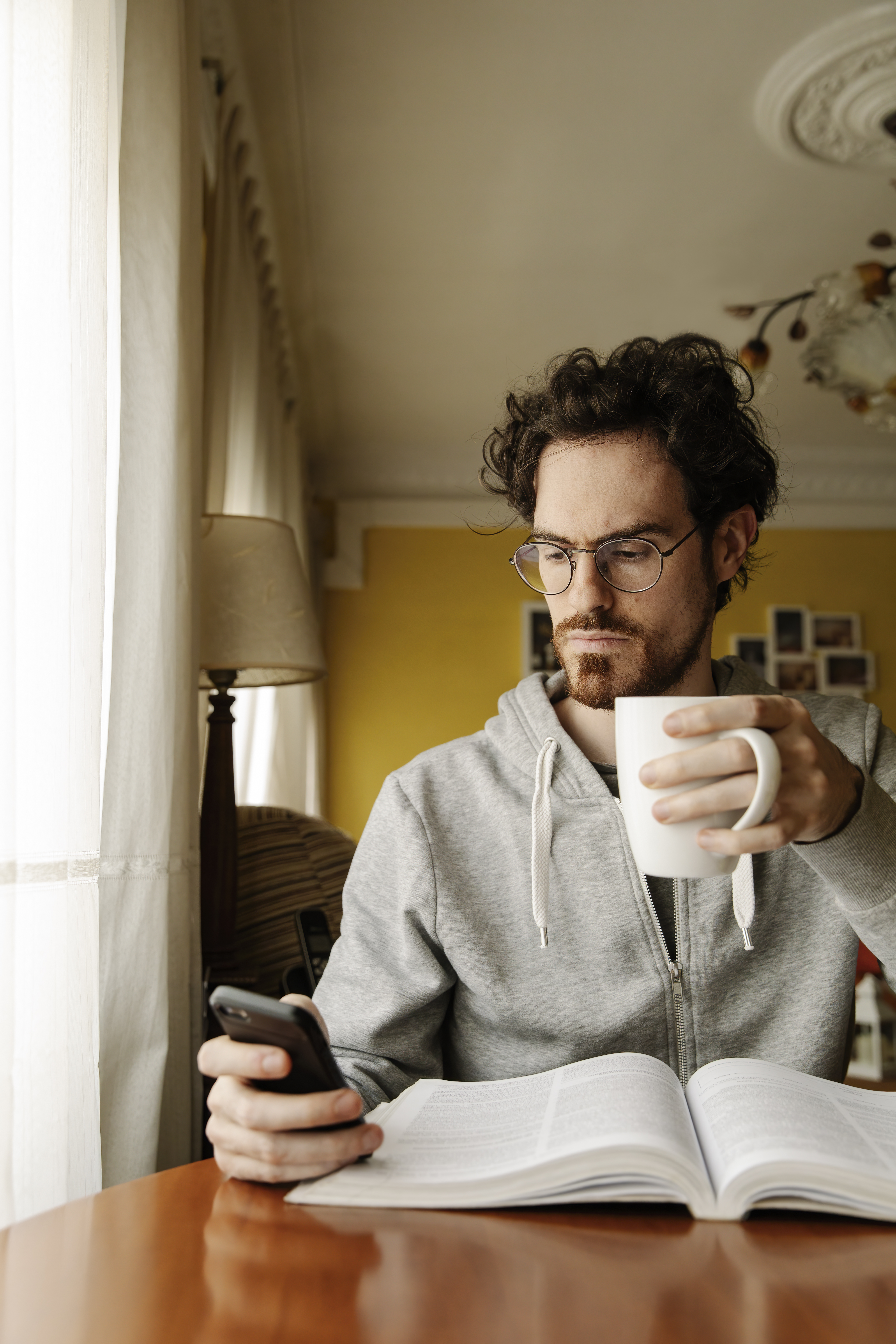 Man reads news on smartphone with book open