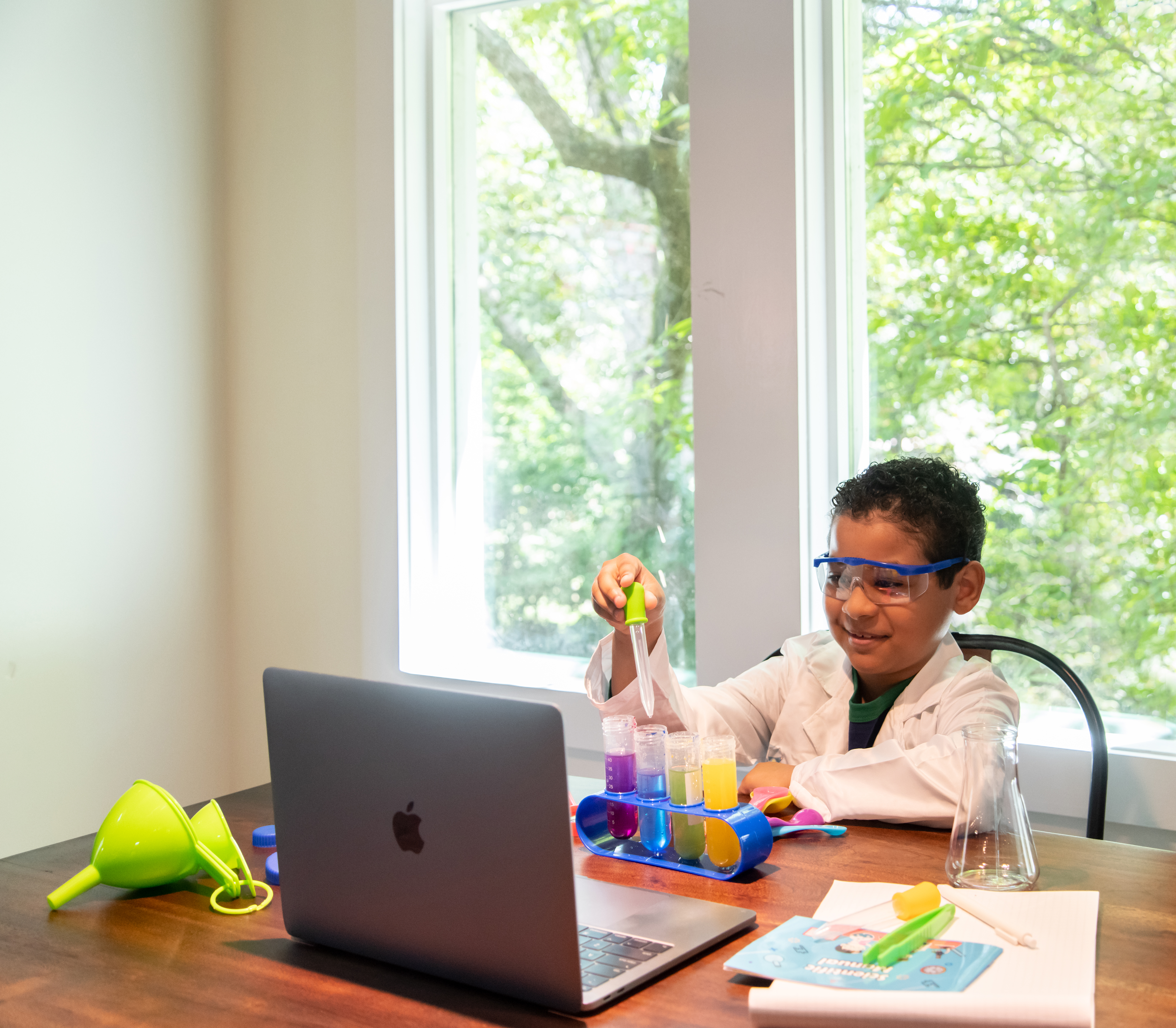 Child doing science experiment in front of laptop