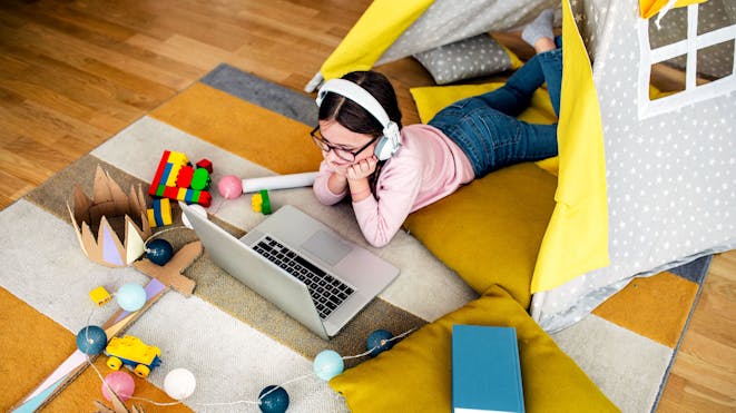 Girl in playroom watching class on laptop Girl in playroom watching class on laptop