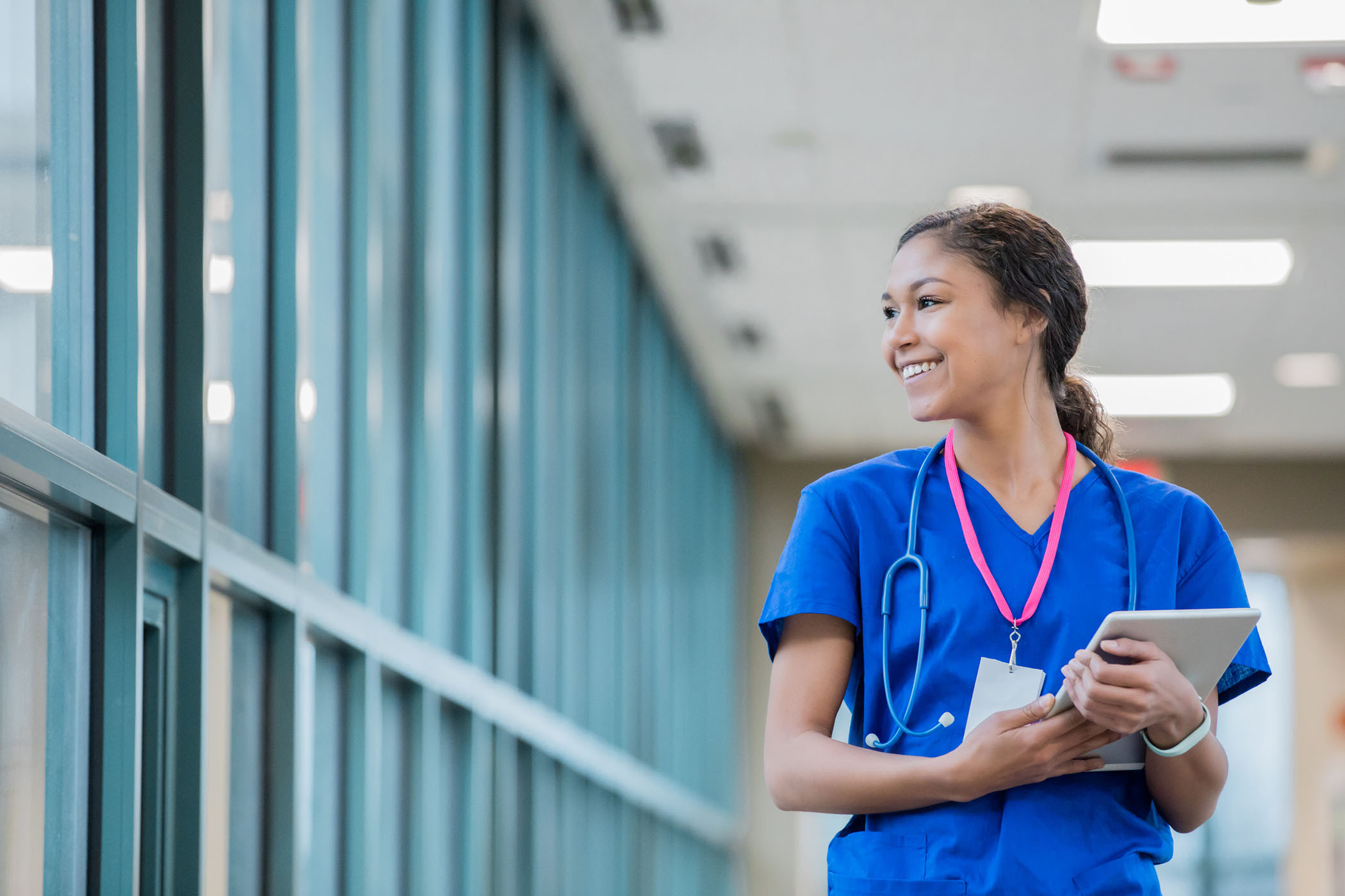 Woman in scrubs looking out window